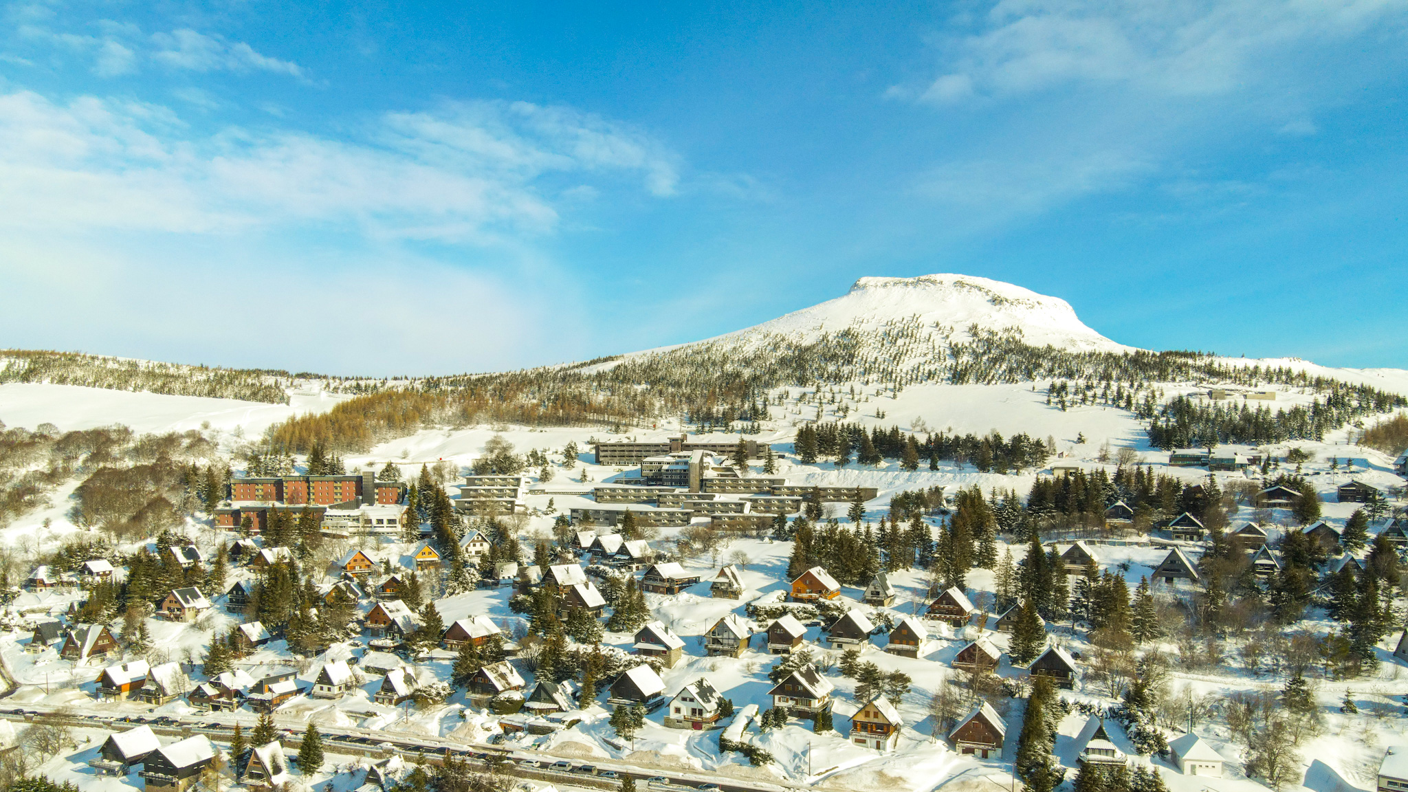 Super Besse: The Puy de Chambourguet watches over a village of snow-covered chalets, a magical scene.